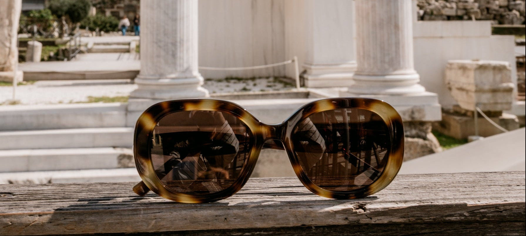 Sunglasses on a ledge with ancient columns in the background